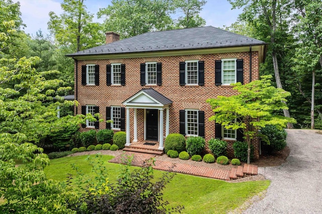 colonial-style house featuring a front yard