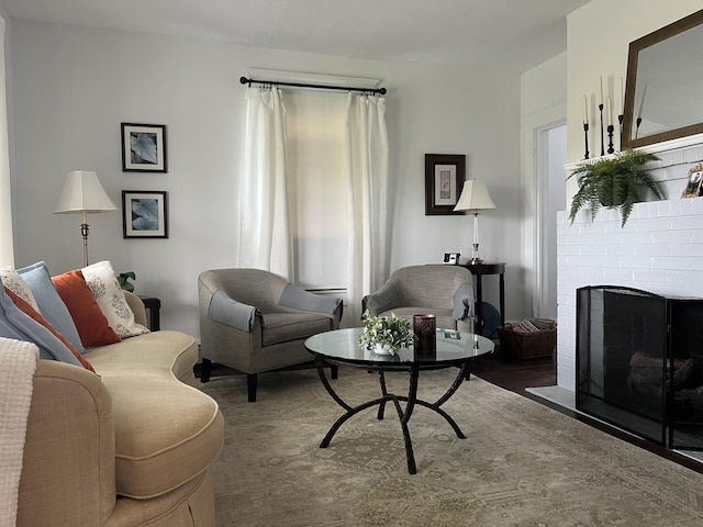 living room featuring a brick fireplace and dark wood-type flooring