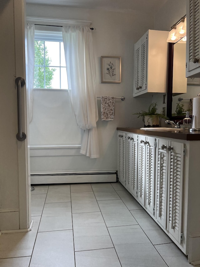 bathroom with baseboard heating, tile patterned floors, and sink