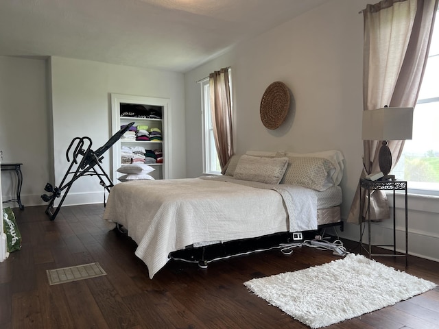 bedroom with dark wood-type flooring and a spacious closet