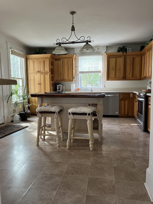 kitchen with a kitchen bar, decorative light fixtures, plenty of natural light, and appliances with stainless steel finishes