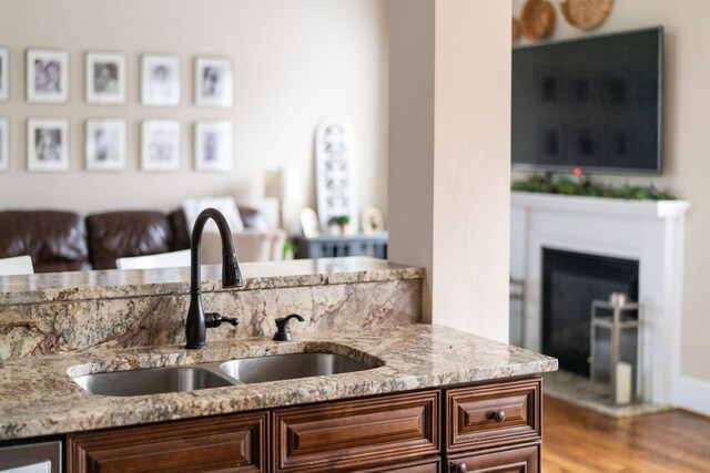 kitchen featuring dishwashing machine, sink, light stone countertops, and hardwood / wood-style floors