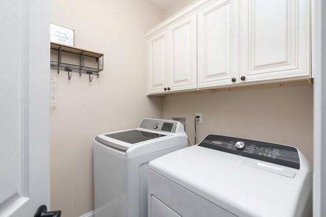 clothes washing area featuring cabinets and washing machine and clothes dryer