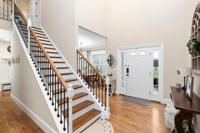 entryway featuring light hardwood / wood-style flooring, baseboard heating, and a high ceiling