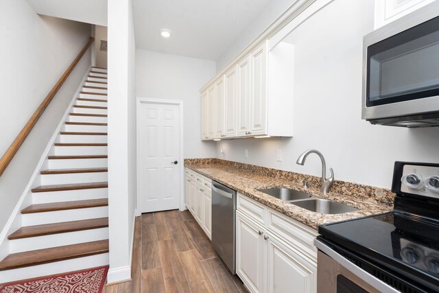 kitchen with stainless steel appliances, white cabinetry, sink, and stone countertops