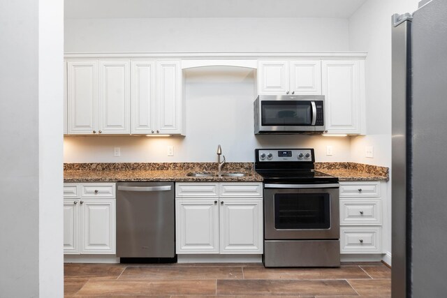 kitchen with dark stone countertops, appliances with stainless steel finishes, sink, and white cabinets