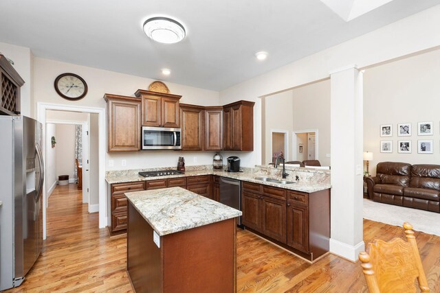 kitchen with stainless steel appliances, sink, kitchen peninsula, and light hardwood / wood-style floors