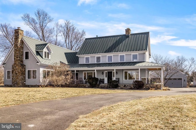 view of front of home featuring a chimney, metal roof, a standing seam roof, a porch, and a front yard