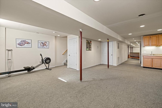 finished below grade area featuring recessed lighting, light colored carpet, a sink, and stairway