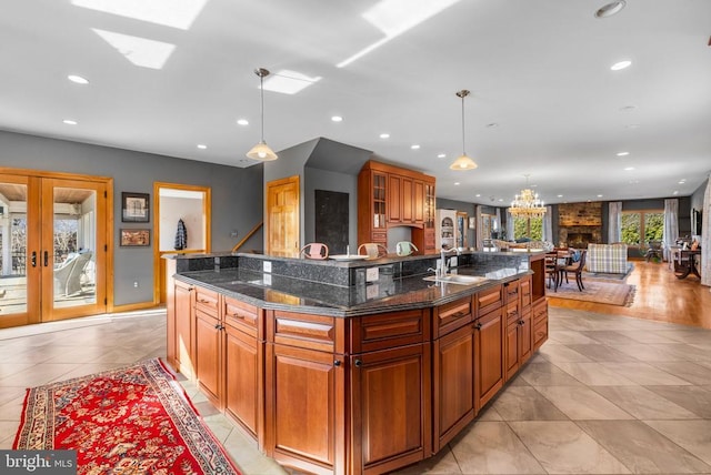 kitchen with french doors, a spacious island, recessed lighting, brown cabinetry, and a sink