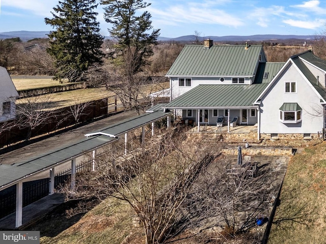 back of property featuring a chimney, metal roof, a standing seam roof, a mountain view, and stucco siding