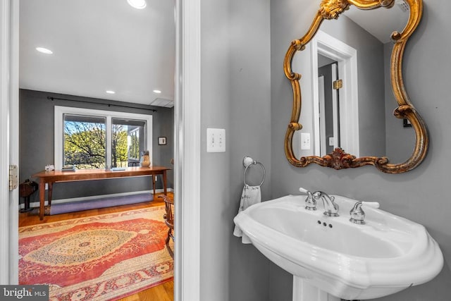 bathroom featuring recessed lighting, a sink, and wood finished floors