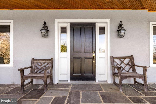 entrance to property featuring a porch and stucco siding