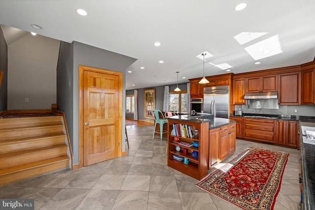 kitchen featuring a skylight, a center island, decorative backsplash, appliances with stainless steel finishes, and under cabinet range hood