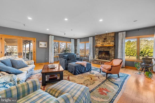 living room with light wood-style floors, recessed lighting, french doors, and a fireplace