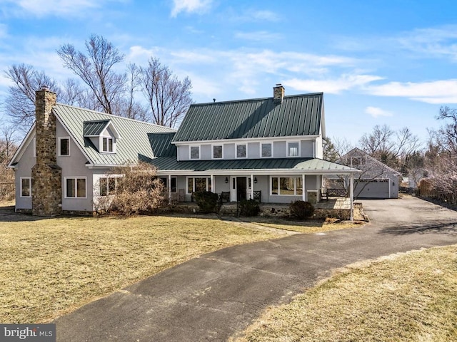 view of front of home featuring an outbuilding, metal roof, covered porch, a standing seam roof, and a chimney