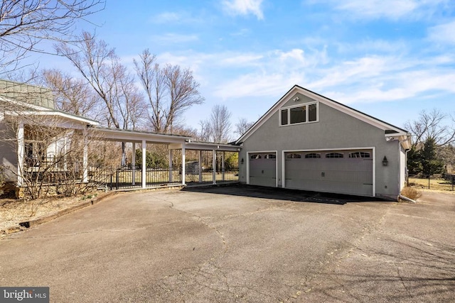 view of side of home featuring a detached garage and stucco siding