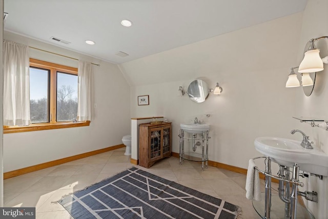 bathroom with baseboards, toilet, tile patterned flooring, vaulted ceiling, and a sink