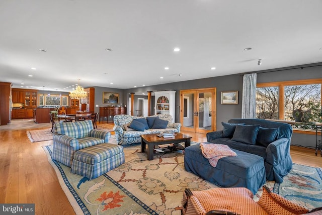 living room with light wood finished floors, french doors, recessed lighting, and a notable chandelier