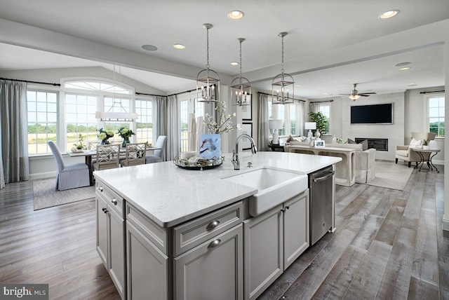 kitchen with a fireplace, wood finished floors, a sink, gray cabinets, and dishwasher