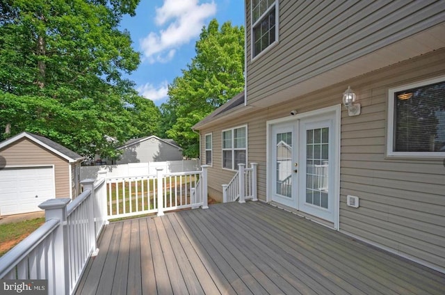 wooden deck featuring an outbuilding, a detached garage, and fence