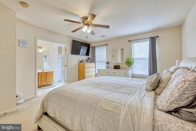 bedroom featuring light colored carpet, visible vents, a ceiling fan, ensuite bath, and baseboards