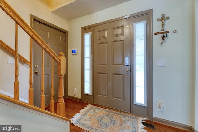 foyer entrance featuring stairway, baseboards, visible vents, and dark wood finished floors