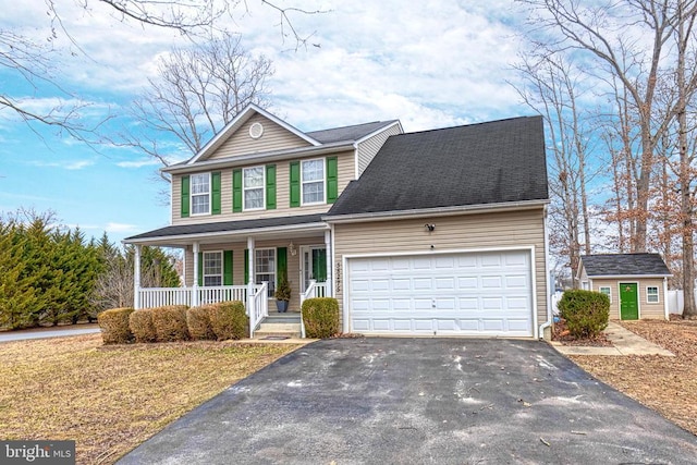 view of front of property with a porch, an outdoor structure, an attached garage, and aphalt driveway