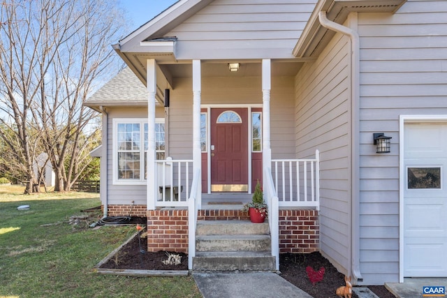 doorway to property featuring covered porch, a shingled roof, and a yard