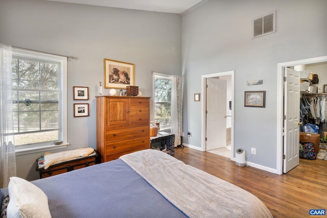 bedroom featuring visible vents, multiple windows, wood finished floors, and a spacious closet