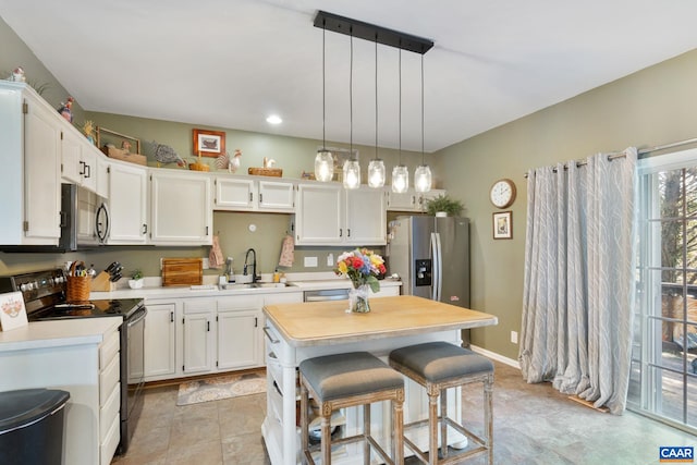 kitchen with a sink, appliances with stainless steel finishes, white cabinets, and light countertops