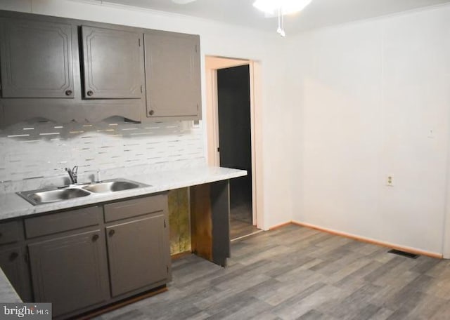 kitchen featuring gray cabinets, sink, light hardwood / wood-style flooring, and backsplash