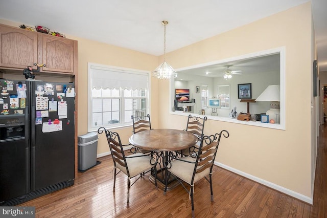 dining room with hardwood / wood-style flooring and ceiling fan with notable chandelier