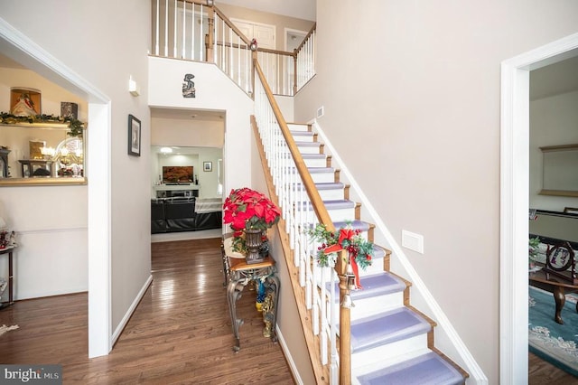 staircase featuring wood-type flooring and a high ceiling