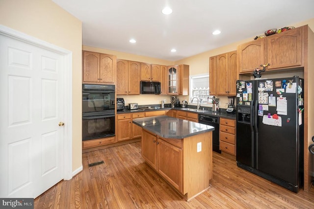 kitchen featuring a kitchen island, sink, light hardwood / wood-style floors, and black appliances