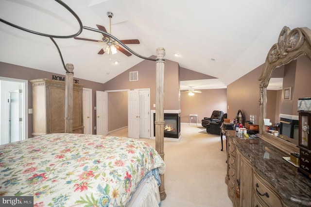 carpeted bedroom featuring lofted ceiling, decorative columns, ceiling fan, and a multi sided fireplace