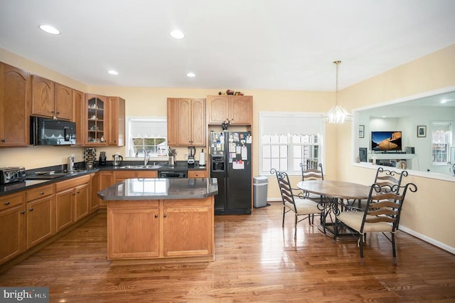 kitchen featuring pendant lighting, sink, hardwood / wood-style flooring, a center island, and black appliances