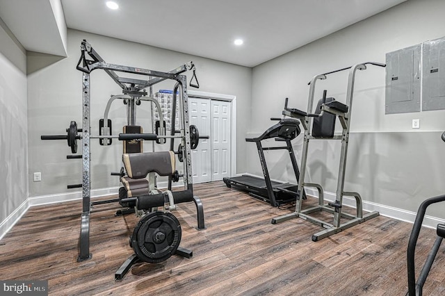 exercise area with recessed lighting, electric panel, wood finished floors, and baseboards