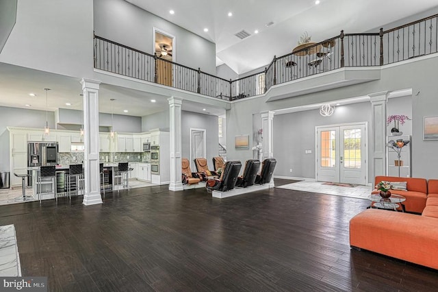 living room with french doors, baseboards, ornate columns, and wood finished floors