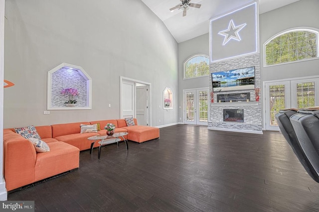 living area with a ceiling fan, baseboards, high vaulted ceiling, a fireplace, and wood-type flooring