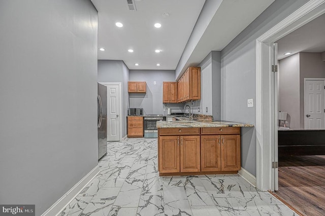 kitchen featuring stainless steel appliances, brown cabinets, and marble finish floor