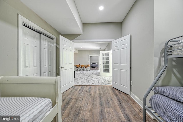 bedroom featuring wood finished floors, baseboards, recessed lighting, french doors, and a closet