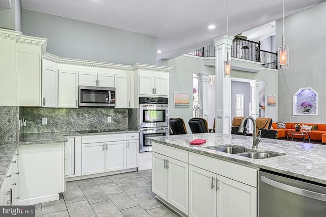 kitchen featuring decorative columns, a sink, stainless steel appliances, white cabinetry, and tasteful backsplash