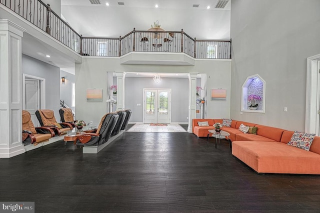 living room with visible vents, a high ceiling, baseboards, and wood finished floors