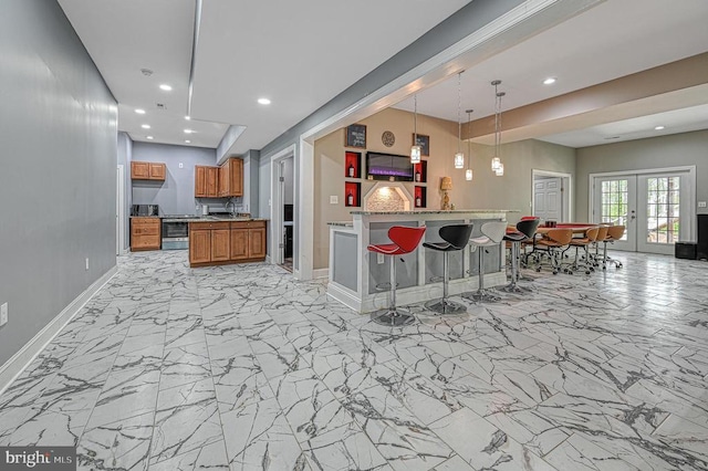 kitchen featuring marble finish floor, open floor plan, french doors, brown cabinetry, and baseboards