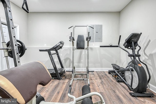 workout room with electric panel, baseboards, and wood finished floors