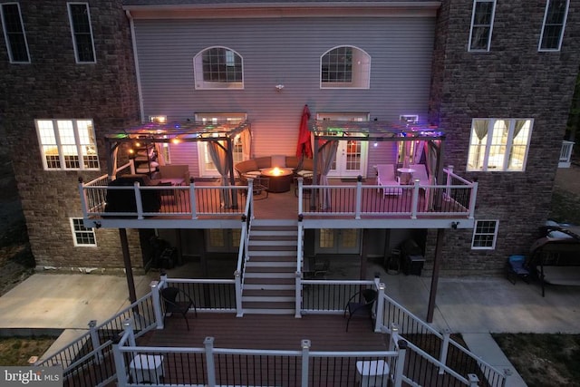 rear view of property featuring stairs, an outdoor fire pit, a patio area, and a wooden deck