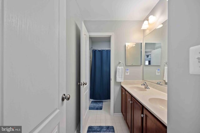 bathroom with tile patterned flooring, a sink, baseboards, and double vanity