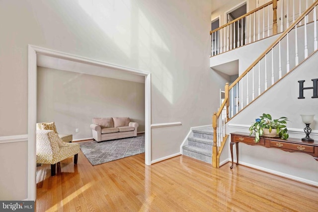 interior space featuring stairway, wood finished floors, a towering ceiling, and baseboards