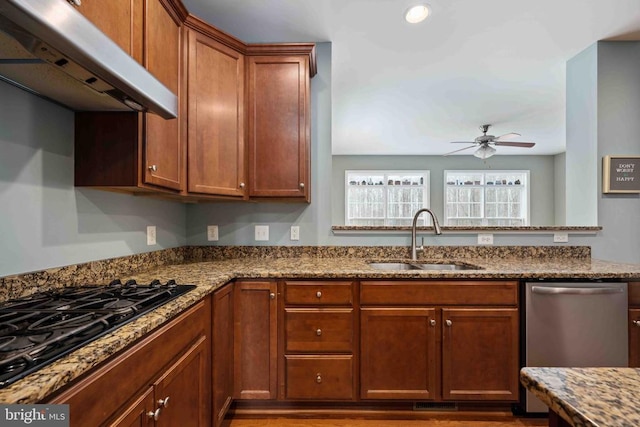 kitchen with light stone counters, a sink, black gas cooktop, under cabinet range hood, and stainless steel dishwasher